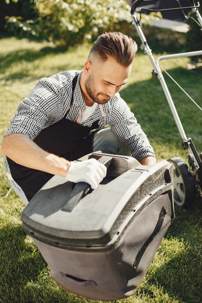 Young man mowing the lawn on a sunny day, focusing on chores and gardening.